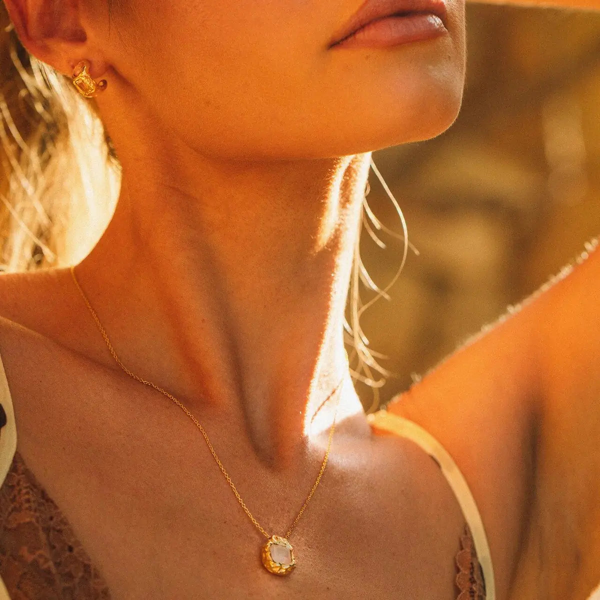 Halskette mit Anh�nger in Gold, Nahaufnahme im Sonnenlicht � Made to Wander